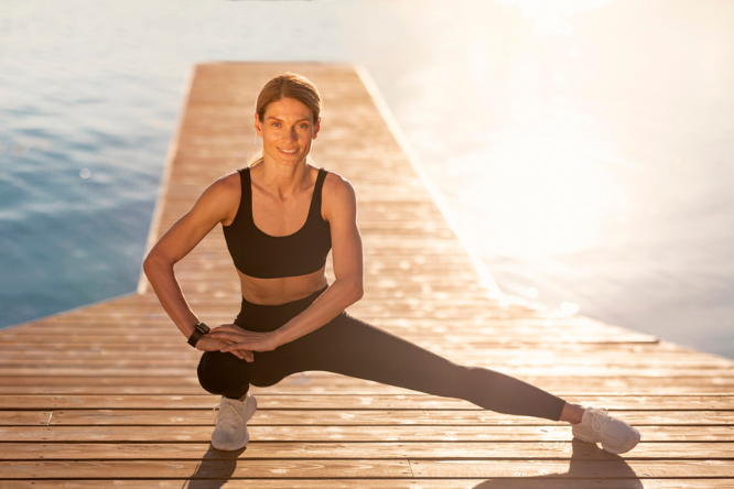 active-woman-outside-stretching-strengthera